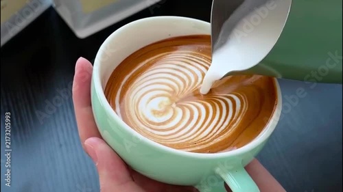 Barista Pouring Steamed Milk into Light Green Cup to Create Rosetta Latte Art