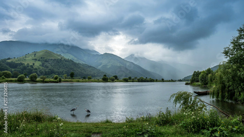 Scenic lake with calm water reflecting cloudy sky and surrounding green