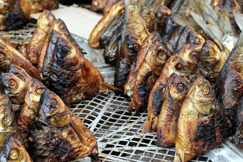 Smoked Fish Heads Arranged on Grate at Outdoor Market Stall, Traditional Preserved Seafood