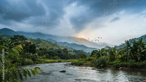 Scenic river flowing through lush green valley with distant mountains