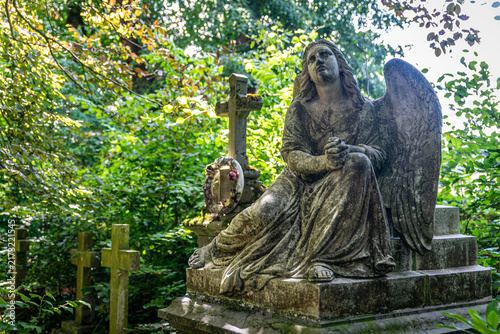 Quadro su tela Statue d'ange en prière sur un tombeau dans un cimetière boisé