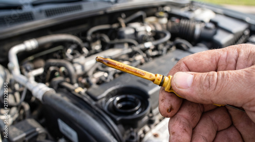 Driver checking oil level with a dipstick in a car engine  