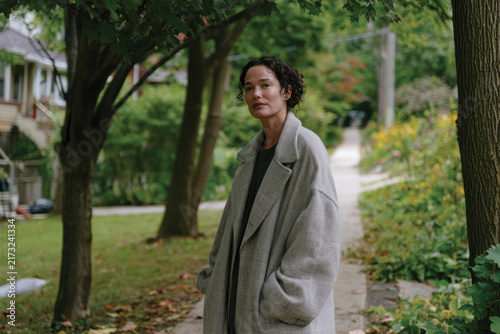 This image features a confident woman standing outside in a beautifully landscaped environment, suggesting a connection to nature and a sense of personal empowerment.