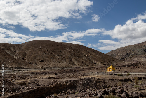 Картината върху платно Yellow house in a rocky mountain valley