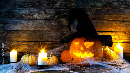 Halloween pumpkins and burning candles on wooden background