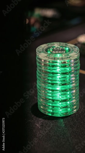 Glowing electronic casino chips stacked on a dark table. Advanced biometric surveillance and digital security monitoring in gaming environments.
