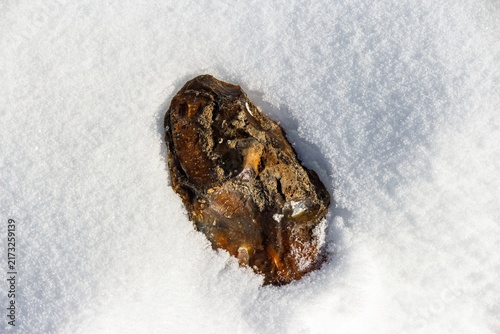 Obraz na plátně Contemporary, roughly knapped flint hand axe emerging from crisp white snow, glistening under bright sun