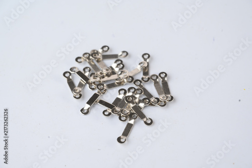 Obraz na płótnie Small metallic electrical connectors scattered on a white surface, used for joining wires in circuits