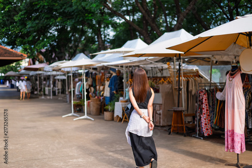 A young woman happily strolls through the Jing Jai Weekend Market in Chiang Mai, Thailand, on a weekend morning.