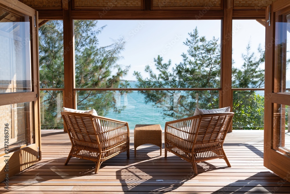 Naklejka premium The Seaside Veranda with Wicker Chairs Overlooking Ocean and Forest