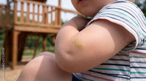 Happy toddler playing outdoors on wooden playground equipment enjoying summer sunshine and childhood memories