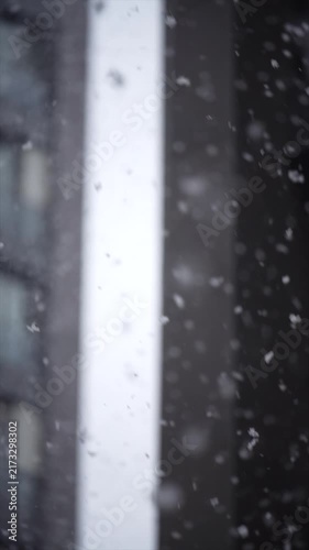 Snow falling in front of a dark blurred background on a cold winter day