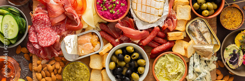 Принти на полотні Enjoy a vibrant charcuterie board filled with assorted cheeses, savory sausages, creamy hummus, nuts, and colorful vegetables