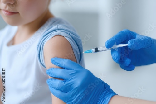 Childhood vaccination. Doctor vaccinating little boy. Kid receiving a Vaccine shot on arm for covid coronavirus, flu, infectious disease. Nurse holds antiviral syringe injection the child in clinic