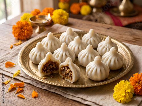 Fresh traditional steamed modaks arranged on a brass plate with coconut and jaggery filling, a popular Indian festive sweet associated with Lord Ganesha and Ganesh Chaturthi.