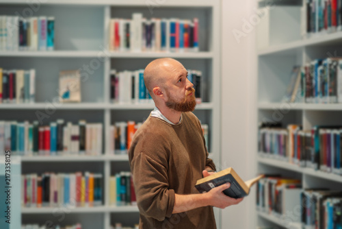 Obraz na płótnie Man glancing aside while reading in a library