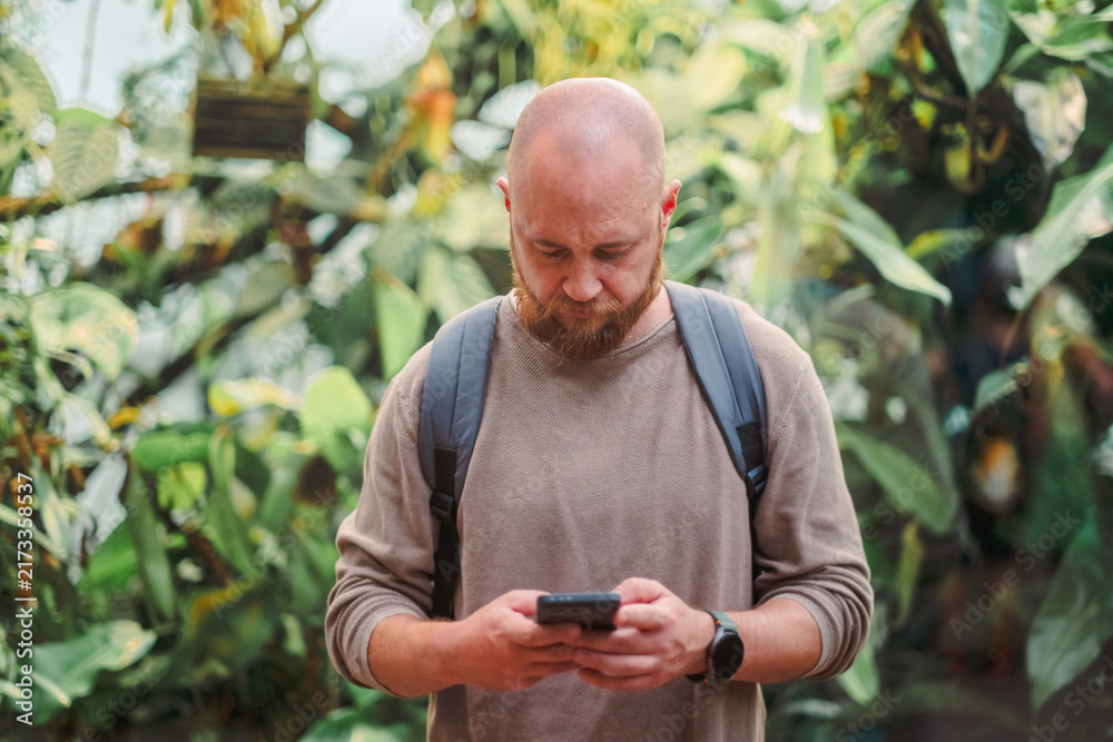 Fototapeta premium Man reading something on his phone inside a greenhouse