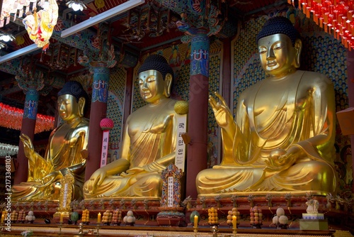 Obraz na plátně Three golden Buddha statues inside an ornate Korean temple hall