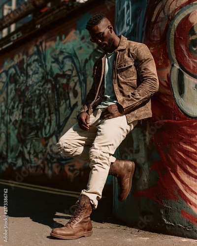 Person sits against a colorful painted wall wearing autumn attire