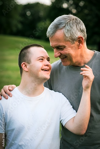 Father and adult son enjoying a loving family moment together in a green outdoor setting