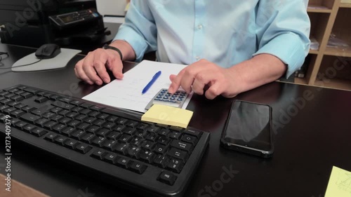 Businessman calculating finances and writing on documents at his office desk