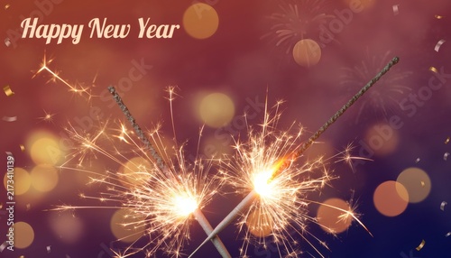 Sparkling sparklers with happy new year text on bokeh background