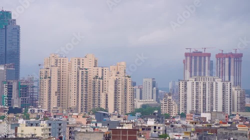 Panning shot of gurgaon cityscape with modern skyscrapers, high-rise construction, dense buildings, and dramatic heavy clouds during the monsoon season.