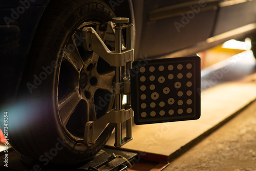 Car wheel alignment target with dot pattern clamped on tire.