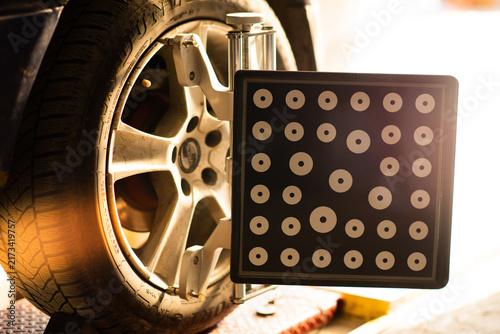 Photography Car wheel alignment target with dot pattern clamped on tire.