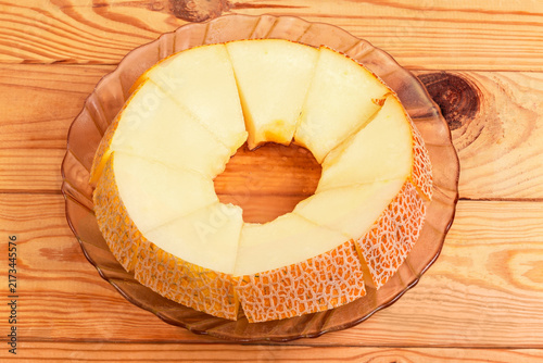 Round piece of melon cut into slices on glass plate