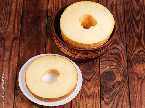 Big annular slice of melon on plate against rest melon