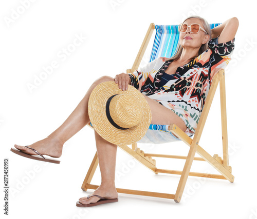 Obraz na plátně Senior woman with hat on deck chair against white background