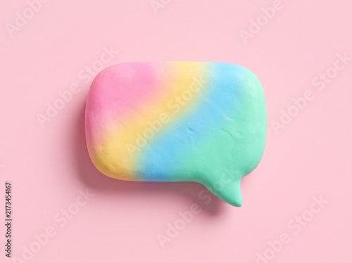 Colorful rainbow speech bubble on a soft pastel pink background creative concept