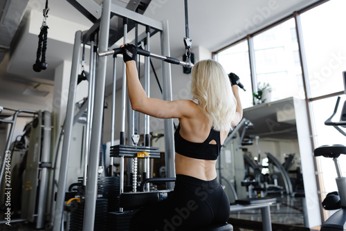 Konstfotografi Athletic woman exercising back muscles using lat machine in gym