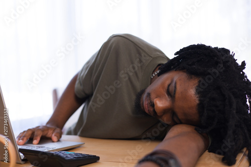 Fotografie Man wearing olive T-shirt slumping with head on forearm at table by window with