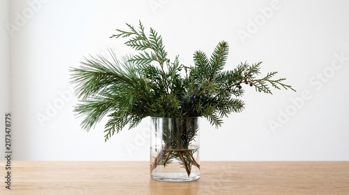Winter Pine Arrangement: A simple yet elegant arrangement of fresh pine and fir branches in a clear glass vase, evoking the serene beauty of a winter forest.
