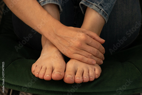 Foto A girl sits on a chair, resting her hand on her bare feet
