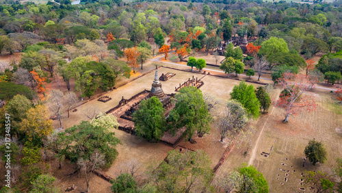 Aerial view of the ancient ruins and stupa at Si Satchanalai Historical Park surrounded by lush trees and dry grass in Si Satchanalai, Sukhothai, Thailand.
