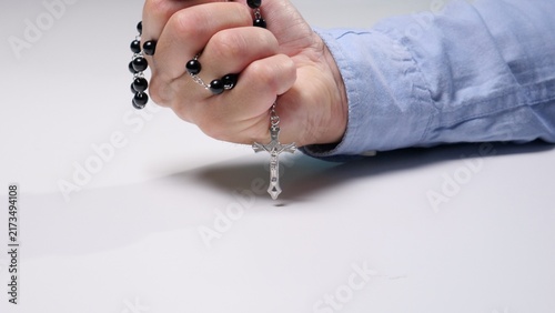 Konstfotografi Person wearing a blue shirt clenching a fist around a rosary with black beads an