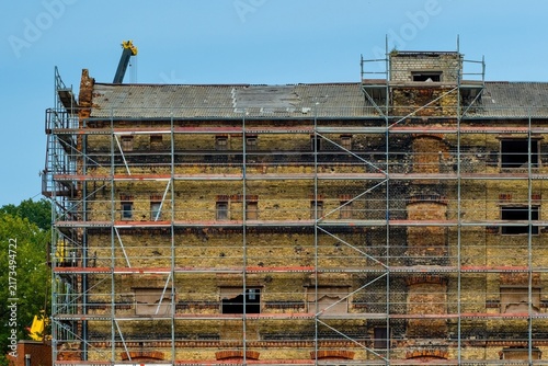 Obraz na płótnie Scaffolding on an old yellow brick industrial building facade under restoration