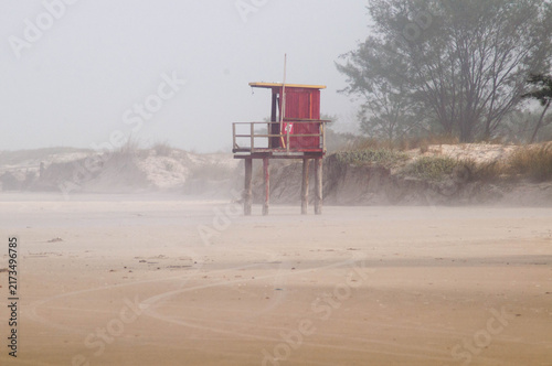 Seaside landscape with red lifeguard tower on sand dune
