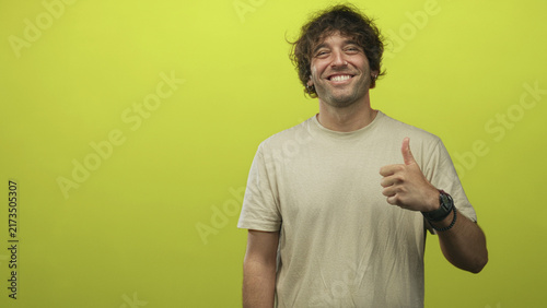 Фотография Man giving thumbs up with bare hand and wristwatch against lime green studio backdrop, smiling broadly and briefly pointing in alternate frames; joy positivity ease