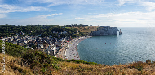 Vista panorámica del pueblo de Etretat , con una playa rodeada de acantilados que ofrecen una vista espectacular de la costa y el arco de piedra característico al atardecer, viajando en verano 2022