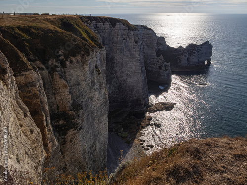 Vista de los acantilados de Etretat en la Normandía de Francia desde arriba, con el sol reflejado en el agua del mar y las montañas a contraluz , viajando en verano de 2022