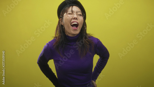 Woman singing with mouth open and hands on hips in studio wearing purple turtleneck and beret; joy spontaneity.