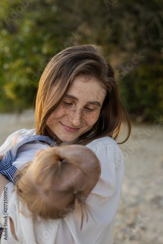 Konstfotografi Mother tenderly holding her sleeping baby outdoors during golden hour