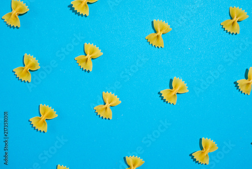 Quadro su tela Farfalle pasta bow ties scattered evenly across a vibrant blue background, creat