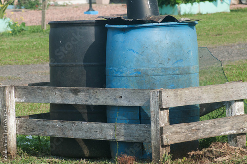 Two large trash blue barrels on a wooden pallet in the street 