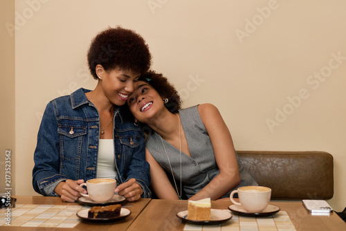 Fotografía Two young African American women share laughter and coffee, embracing friendship