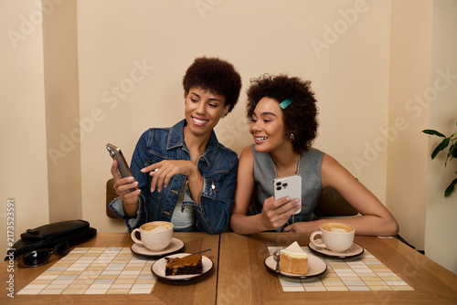 Obraz na plátně Two beautiful young African American women share smiles while sipping coffee and